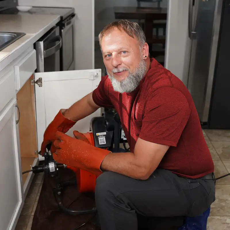 Plumber kneeling fixing a sink