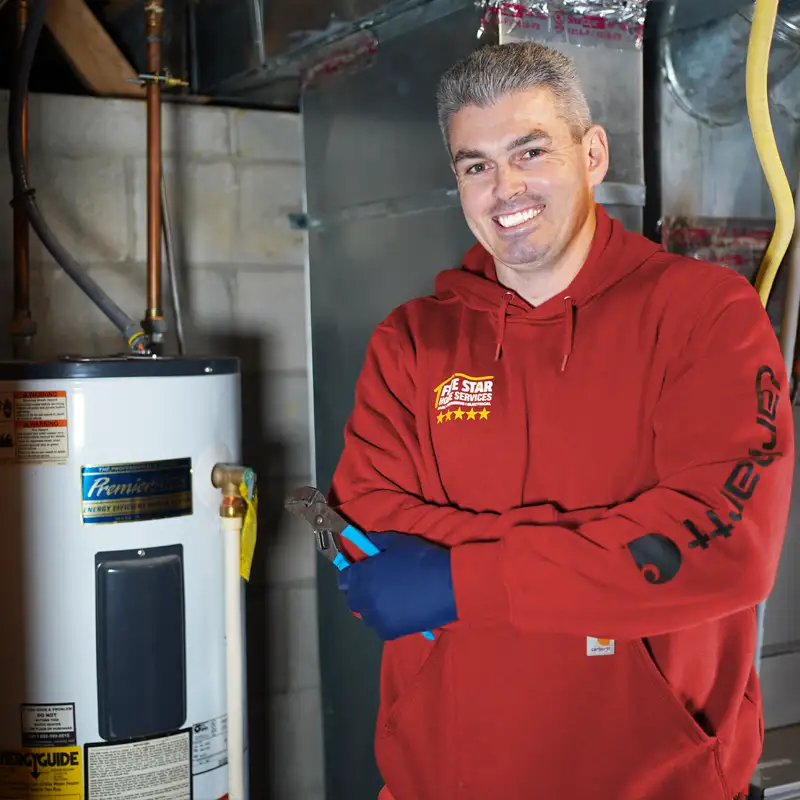 Plumber holding a wrench standing next to a water heater