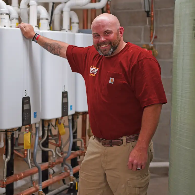 Plumber standing next to a tankless water heater