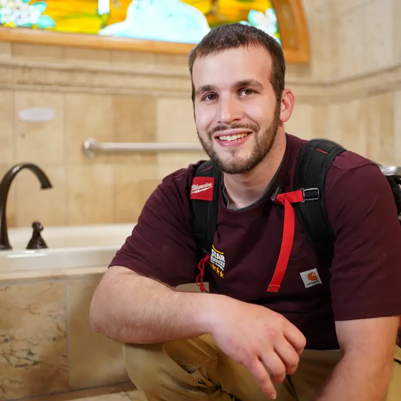 Plumber kneeling in front of a bathtub