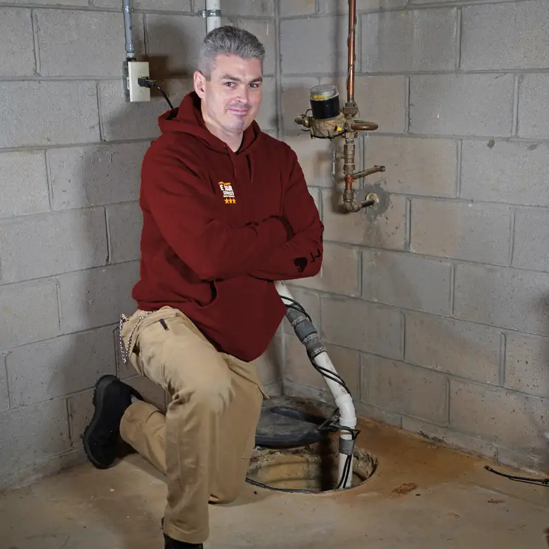 Plumber kneeling next to a sump pump