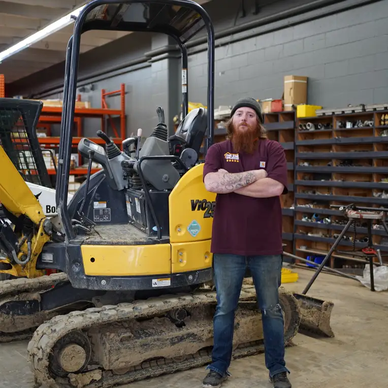 Plumber standing next to an excavator