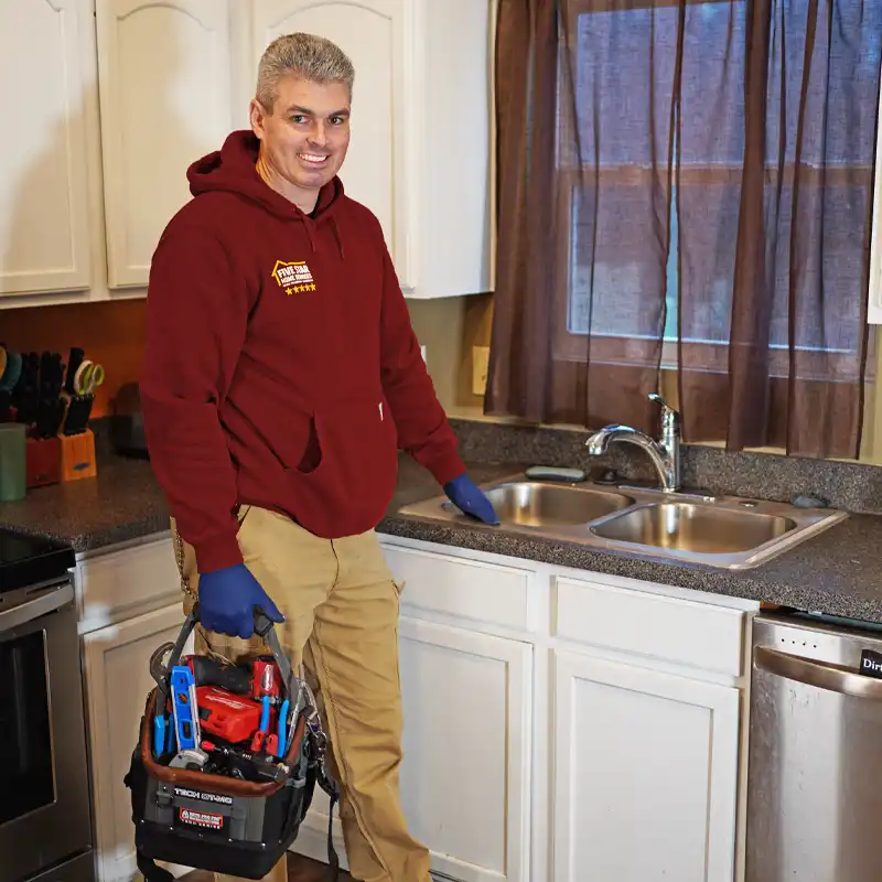 Plumber with tools standing next to a sink